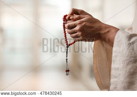 Muslim Man With Misbaha Praying On Blurred Background, Closeup. Space For Text