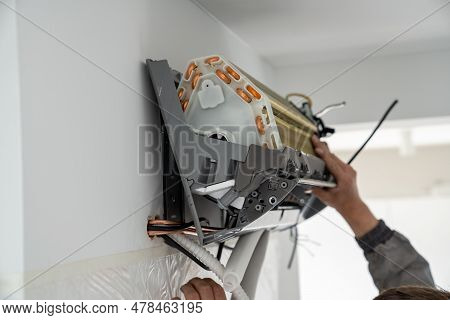 Hands Of Man Technician In Uniform Installing Air Conditioner In Apartment On Wall. Maintenance And 