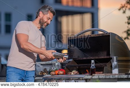 Handsome Man Preparing Barbecue Grill Outdoor. Man Cooking Tasty Food On Barbecue Grill At Backyard.