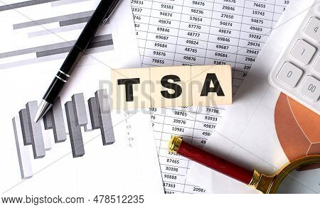 Tsa Text On Wooden Block On A Graph Background With Pen And Magnifier