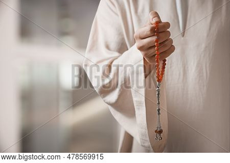 Muslim Man With Misbaha Praying On Blurred Background, Closeup. Space For Text