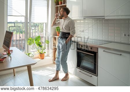 Man In Sick Leave Drinking Water At Home On Kitchen Wearing Back Support Belt Corset On Lower Back T
