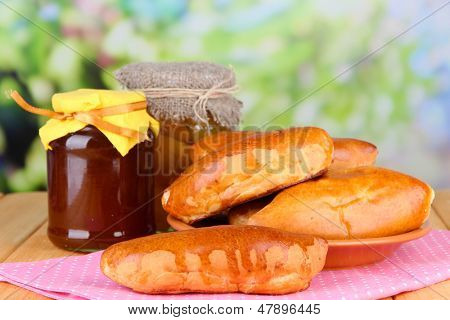 Empanadillas al horno frescos con mermelada de frutas, en la mesa de madera, sobre fondo brillante