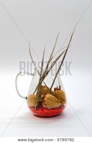 skleněná váza s suchých růží a červené oblázky