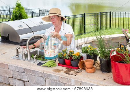 Lady Filling A Watering Can On An Outdoor Patio