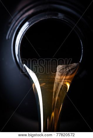 Motor oil pouring over black background