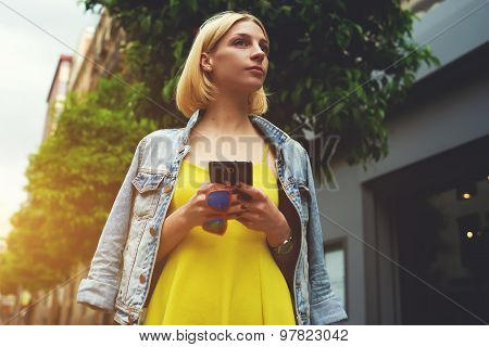 Charming hipster girl chatting for meet a friend while standing in the city with beautiful trees
