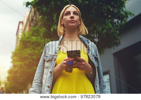 Female tourist use smart phone for navigation to check out the sights while standing in the city