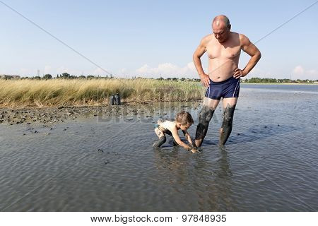 Grandchild Applying Clay On His Grandfather Leg