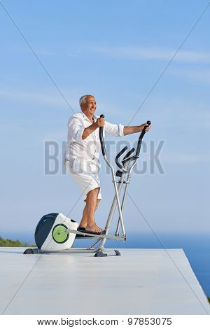 healthy senior man working out on gym treadmill machine at modern home terace with ocean view