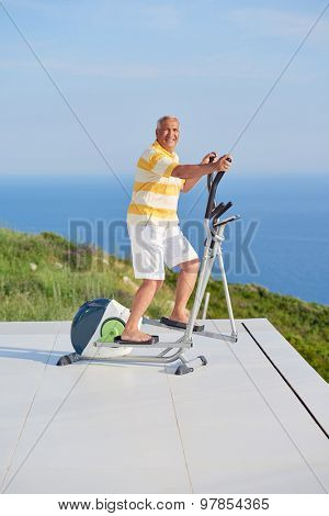 healthy senior man working out on gym treadmill machine at modern home terace with ocean view