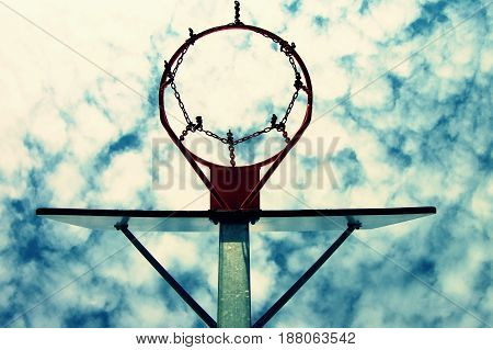 Old Neglect Basketball Backboard With Rusty Hoop Above Street Court. Blue Cloudy Sky In Bckground. R