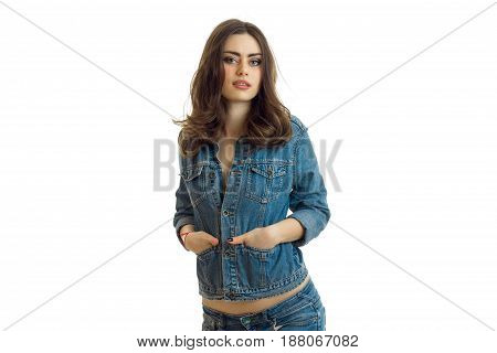 beautiful young brunette stands in jeans jacket and looks into the camera close-up isolated on white background