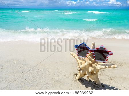 Patriotic USA background with starfish in the sunglasses on the sandy beach