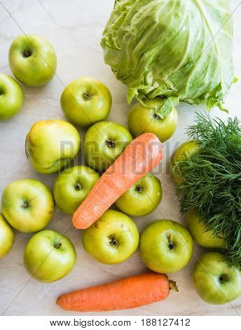 Carrots orange green apples dill and cabbage on the table. Close-up view. View from above