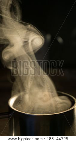 Over a metal mug of thermos with coffee to steam