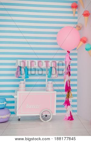 Children's zone with sweets: lollipops, ice cream, macarons, balloon and candy bar. Children room with blue stripe background.