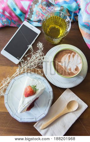 coffee cup and delicious cake strawberry and relax time moblie on table in coffee shop