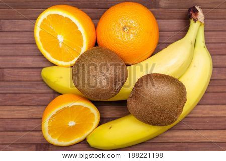 Fresh fruits banana, kiwi, orange isolated on wooden background. Healthy food. A mix of fresh fruit. Group of citrus fruits. Vegetarian raw fruit. Nutrition for a healthy lifestyle.