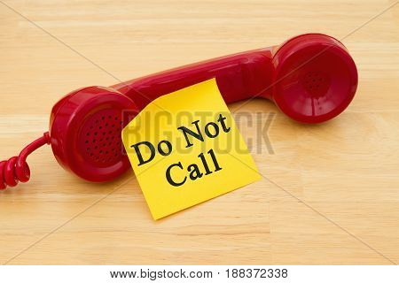 Getting on the do not call list Retro red phone handset with a yellow sticky note and text Do not call
