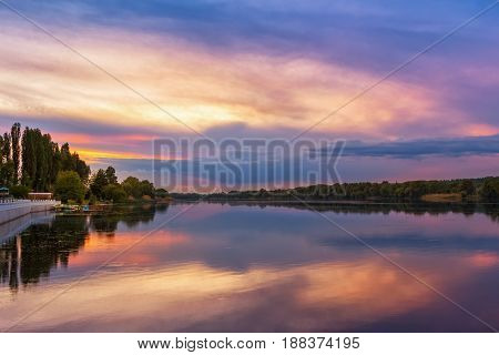 Vivid scenery of sunset at the river colorful dramatic evening sky reflected in the water hdr image. Khmelnytskyi Ukraine.