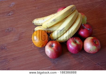 Fruit bananas apples orange on a wooden table background