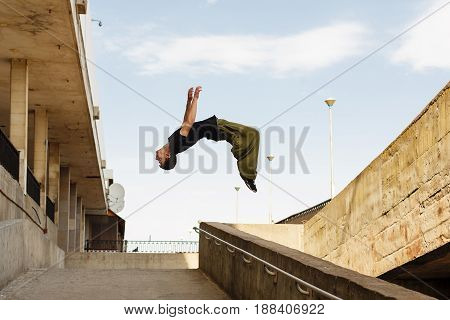 Young man back flip. Parkour in the urban space. Sport in the city. Sport Activities outdoors. Acrobatics