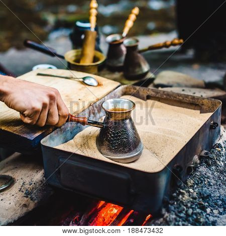 Man Is Cooking Turkish Coffee In The Box With Sand Under Live Coals