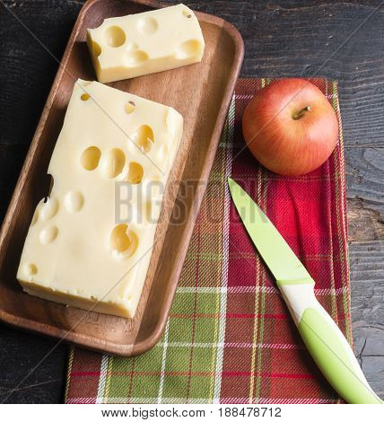 A Piece Of Emmethal Swiss Cheese Over A Wooden Rustic Plate, A Green Knife And A Fresh Appe.