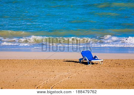 Summer. The shore of the ocean. One blue trestle-bed stands in the surf zone. Sand and wave