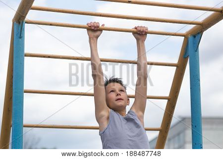 A Teenager In A T-shirt Is Engaged In Gymnastics On A Horizontal Bar