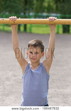 A Teenager In A T-shirt Is Engaged In Gymnastics On A Horizontal Bar