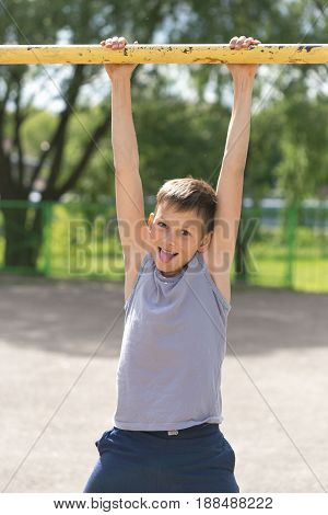 A Teenager In A T-shirt Is Engaged In Gymnastics On A Horizontal Bar