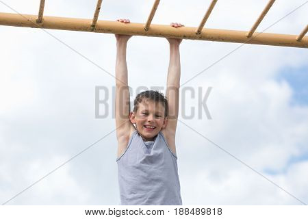 A Teenager In A T-shirt Is Engaged In Gymnastics On A Horizontal Bar