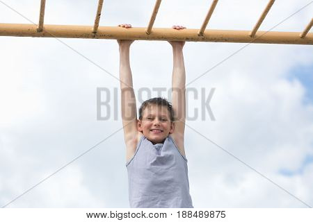A Teenager In A T-shirt Is Engaged In Gymnastics On A Horizontal Bar