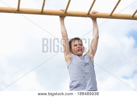 A Teenager In A T-shirt Is Engaged In Gymnastics On A Horizontal Bar