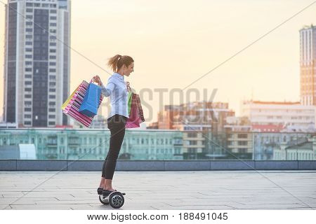 Young woman with shopping bags. Female riding hoverboard.