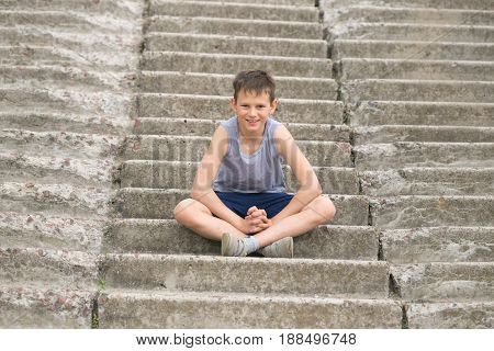 A Teenager In A T-shirt Sits On Concrete Steps