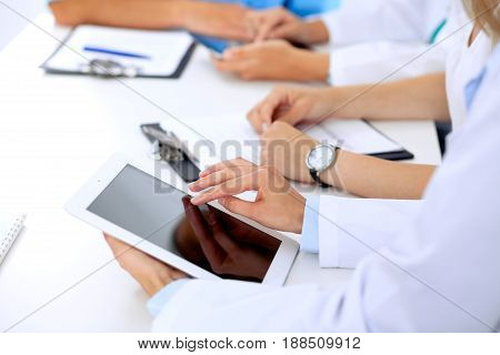 Group of doctors at medical meeting. Close up of physician using tablet computer