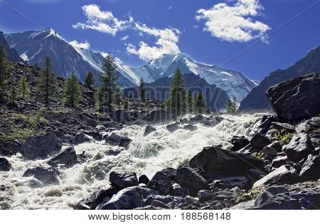 Mountain stream with breakneck speed rushing into the valley paving its course between huge boulders