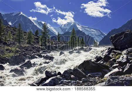 Mountain stream with breakneck speed rushing into the valley paving its course between huge boulders