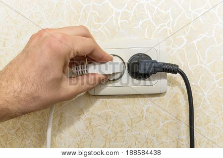 Close-up shot of male hand putting plug into socket