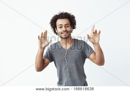 Cheerful african man listening to music in headphones dancing singing. White background.