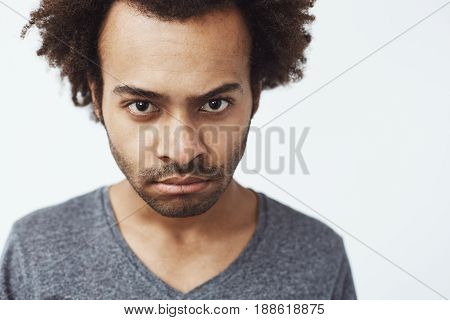 Close up photo of displeased african man looking at camera brutally. White background. Copy space.