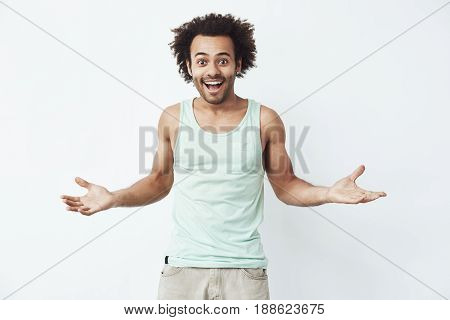 Cheerful handsome african man smiling gesturing looking at camera over white background.