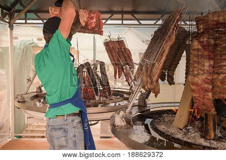Cook prepares the meat to roast on the grill. Argentine asado.