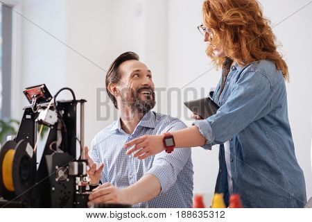 Friendly relationships. Happy cheerful delighted colleagues looking at each other and smiling while enjoying working together