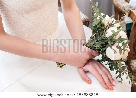 Bride in white drss with wedding bouquet of white peonies in hand