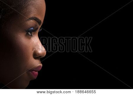 Side view portrait of dark skinned model on a black background. Close up portrait of dark skinned female with bright make up. Side view portrait of beautiful model with bright make up.