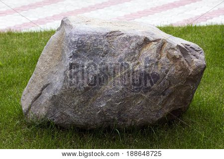 Big granite stone on the green lown grass.